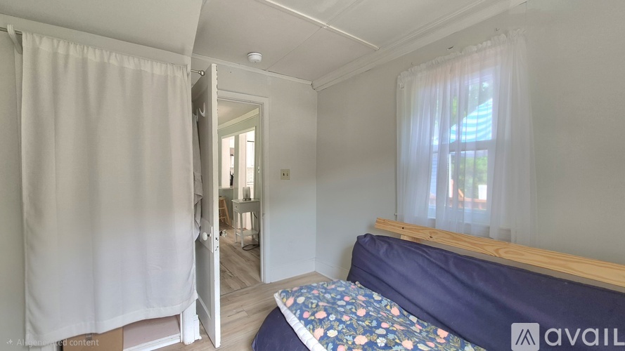 A bedroom with a bed and a window with curtains.