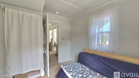 A bedroom with a bed and a window with curtains.