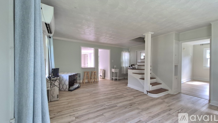 A spacious living room with wooden floors and a staircase leading to another room.