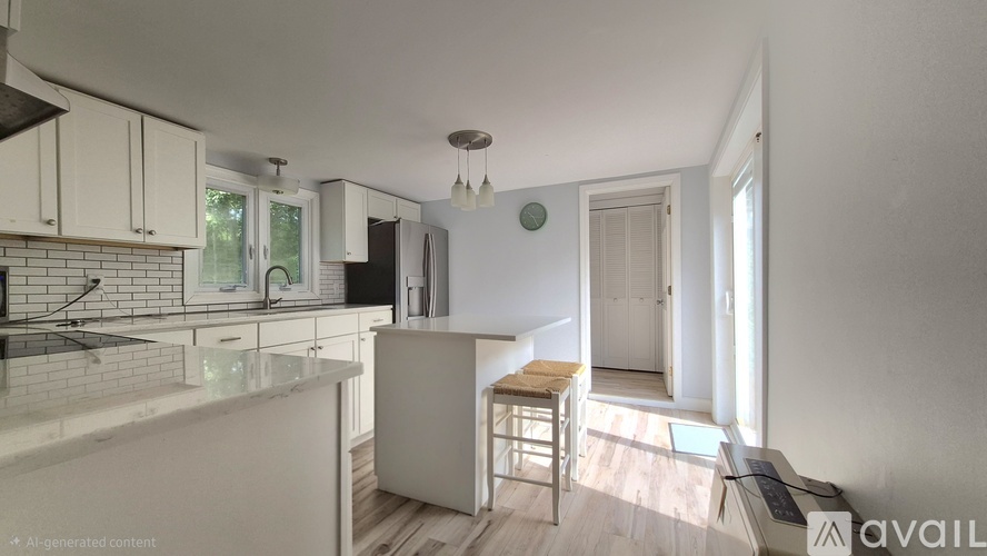 A kitchen with white cabinets and a white countertop with a bar stool in front of it.