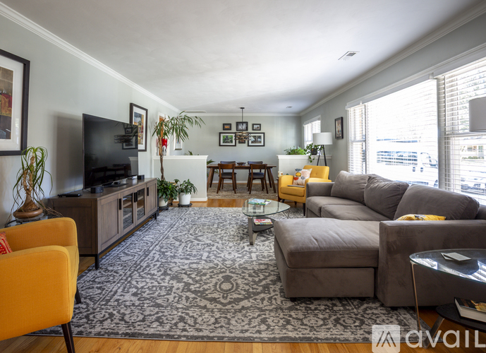A living room with a grey sofa, a yellow chair, a black television and a rug.