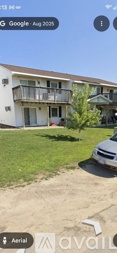 A white building with a balcony and a tree in front of it.