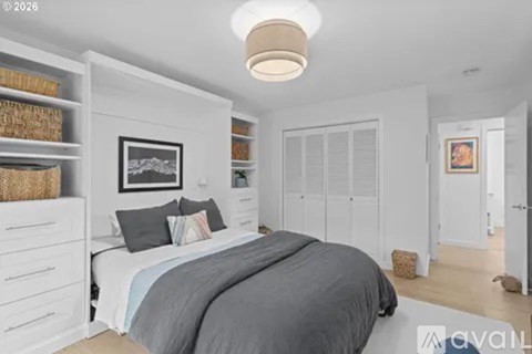 A bedroom with a large bed and a picture on the wall.