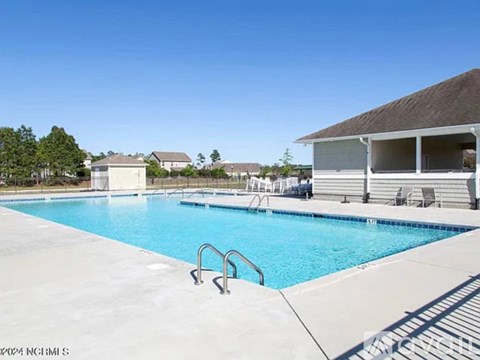 A swimming pool with a diving board and a building in the background.