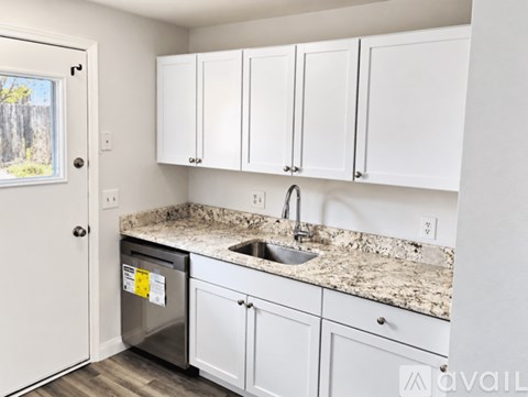 A kitchen with white cabinets and a granite countertop.