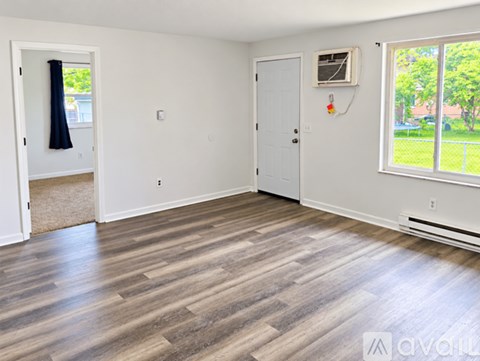 A room with wooden flooring and white walls.