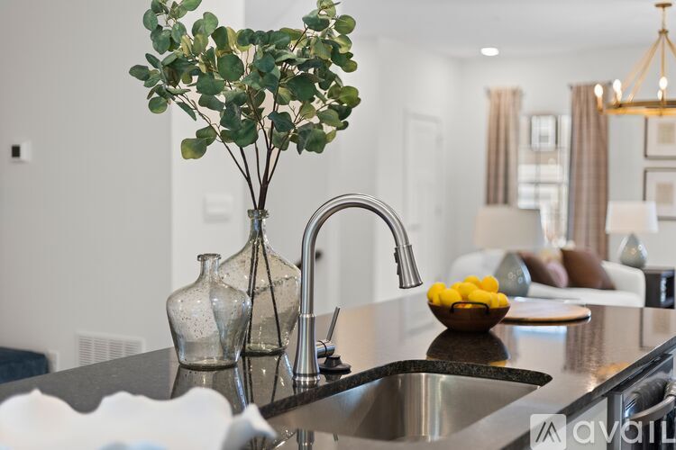 A kitchen counter with a vase of greenery and a bowl of lemons.