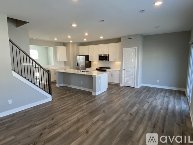 A spacious kitchen with white cabinets and a wooden floor.