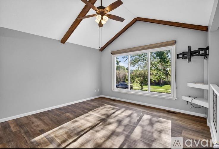 A room with a ceiling fan and a window showing an outdoor view.