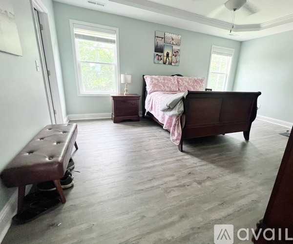 A bedroom with a bed, bench, and pictures on the wall.