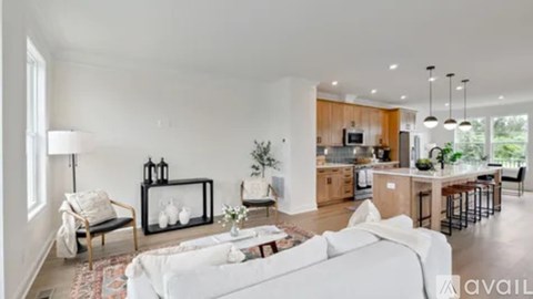 A modern living room with a white sofa and a kitchen in the background.