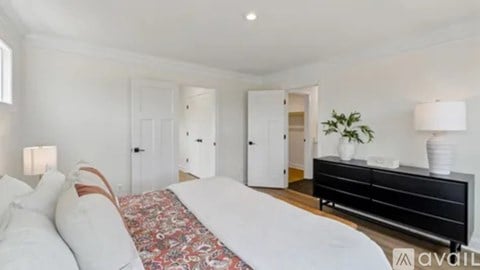 A bedroom with a large bed and a dresser with a plant on top.