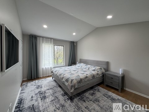 A bedroom with a large bed and a window with curtains.
