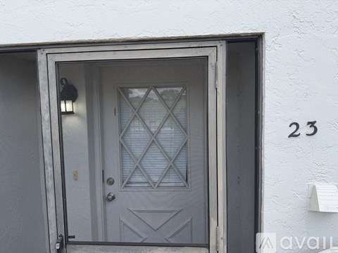A grey door with a diamond pattern on the glass and a number 23 on the wall.