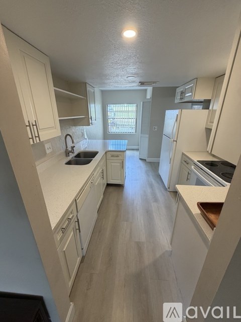 A kitchen with white cabinets and a window.
