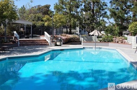 A pool surrounded by trees and a gazebo.
