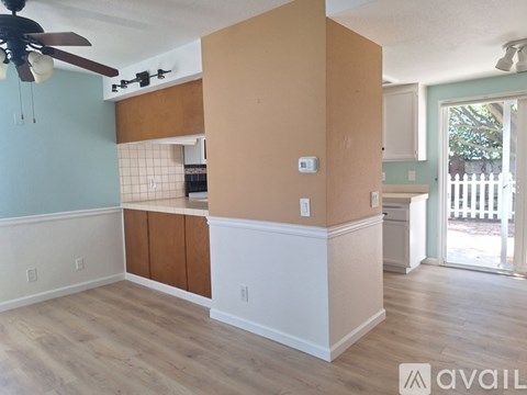 A room with a ceiling fan and a kitchenette.
