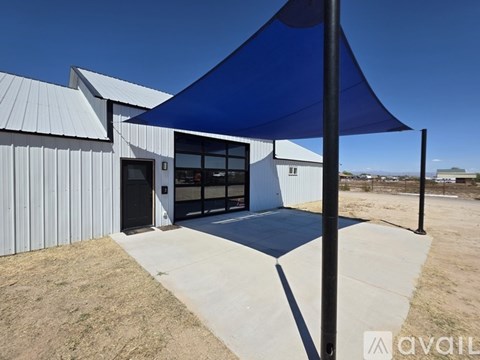 A blue shade structure is in front of a white building.