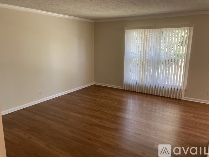 A room with wooden flooring and a window with blinds.