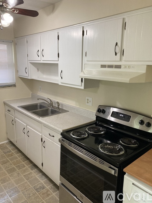 A kitchen with white cabinets and a black stove top oven.