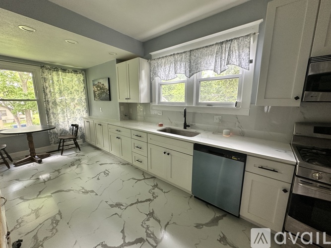 A kitchen with marble flooring and white cabinets.