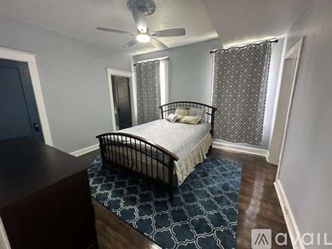 A bedroom with a bed, a ceiling fan, and a patterned rug.