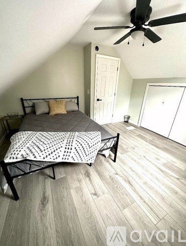 A bedroom with a bed, chair, and ceiling fan.