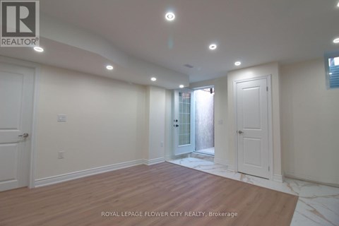 A room with white walls and wooden flooring, with a door in the background.