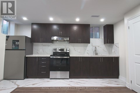 A modern kitchen with dark wood cabinets and a marble backsplash.