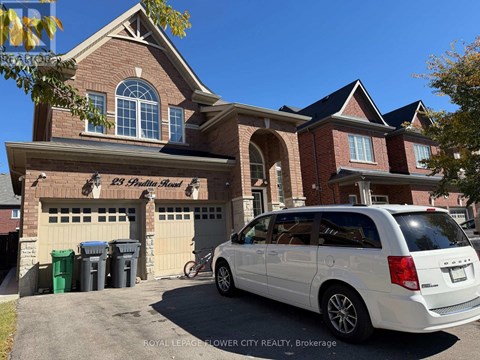 A white minivan is parked in front of a brick building.