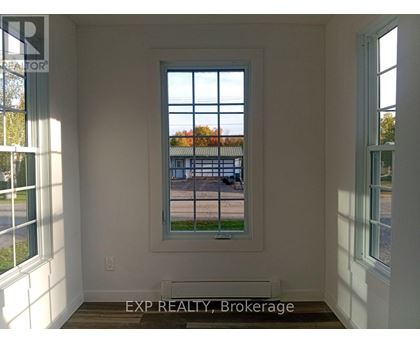 A room with a window showing a view of a street with cars and houses.
