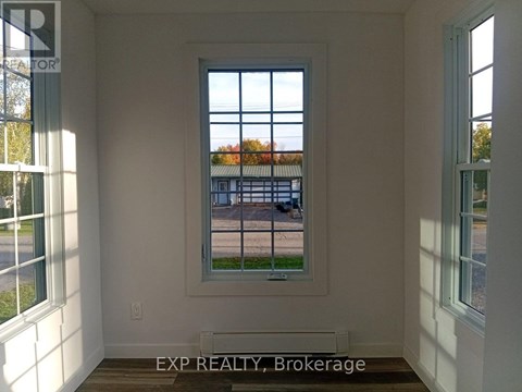 A room with a window showing a view of a street with cars and houses.