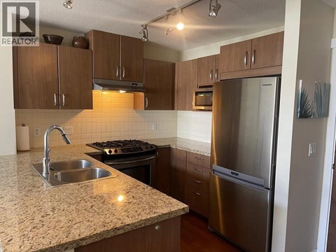 A kitchen with a granite countertop and stainless steel appliances.