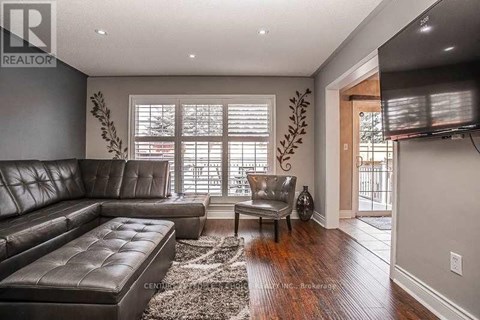 A living room with a leather couch and a flat screen TV mounted on the wall.