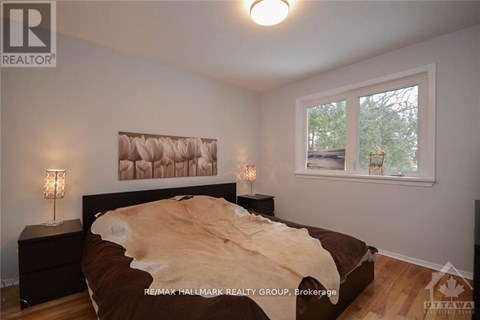 A bedroom with a bed, two lamps, and a painting on the wall.