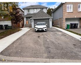 A white car is parked in a driveway.