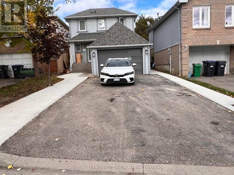 A white car is parked in a driveway.