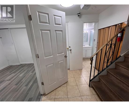 A white door is open to a hallway with a staircase on the right.