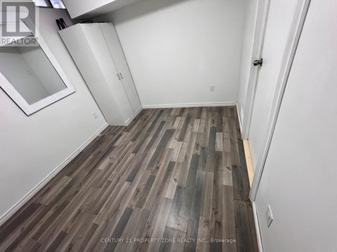 A room with wooden flooring and white walls.