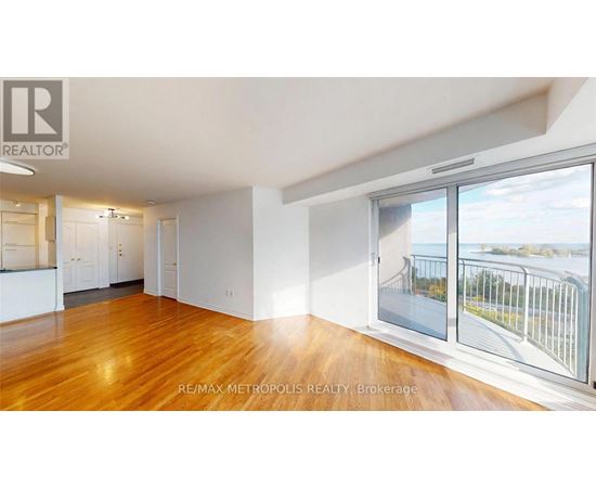A spacious room with wooden floors and a view of a bridge through the window.