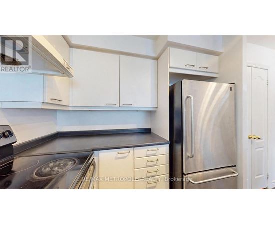 A kitchen with white cabinets and a stainless steel refrigerator.
