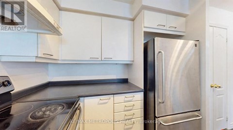 A kitchen with white cabinets and a stainless steel refrigerator.