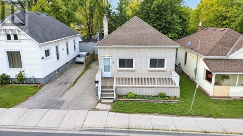 A white house with a porch is in the foreground of a residential street.