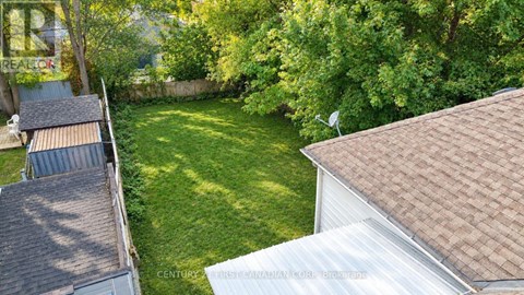 A backyard with a white house and a green lawn.