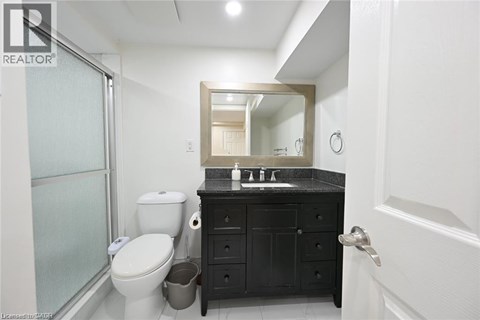 A bathroom with a toilet, sink, and mirror.