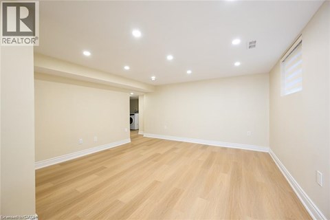 A spacious room with wooden flooring and recessed lighting.