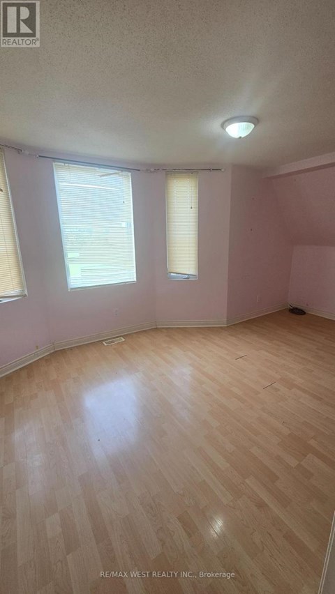 A room with a wooden floor and a window with blinds.