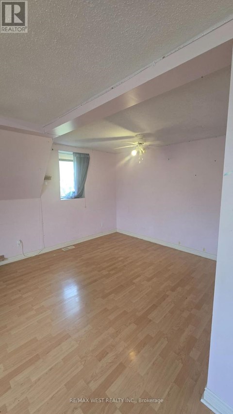 A room with wooden flooring and a window with white curtains.