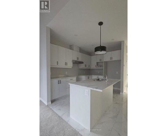 A kitchen with white cabinets and a marble floor.