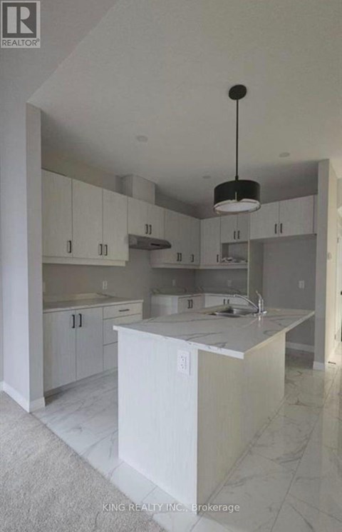 A kitchen with white cabinets and a marble floor.